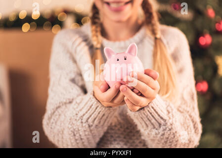 7/8-Ansicht der weiblichen Youngster Holding rosa Sparschwein Stockfoto