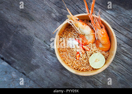 Instant nudeln Suppe mit Garnelen in Houten auf Holz Hintergrund Würzige, Tom Yum Kung Stockfoto