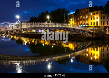 Nacht Blick auf berühmte beleuchtet Ha Penny Bridge in Dublin, Irland mit Reflexion im Fluss Stockfoto