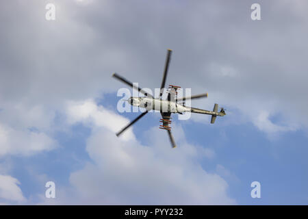 Kampfhubschrauber auf blauer Himmel mit weißen Wolken. Ansicht von unten. Stockfoto
