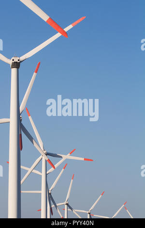 Vertikale Ansicht von vorne der Reihe weiß äolischen Windenergieanlagen in einem Energie Farm gegen einen klaren blauen Himmel mit Copyspace Stockfoto
