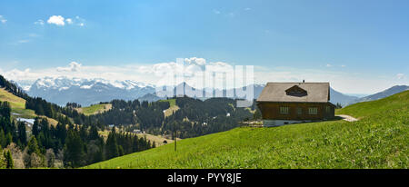 Wunderschöne Schweizer Landschaft mit Hütte und die schneebedeckten Alpen im Hintergrund vom Hochstuckli Höhepunkt im Kanton Schwyz gesehen Stockfoto