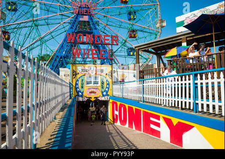 NEW YORK CITY - ca. Juni 2017: Besucher durch einen Tunnel zwischen dem Coney Island boardwalk im Vergnügungspark mit Fahrgeschäften gefüllt Stockfoto