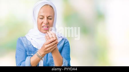 Mittleres Alter östlichen arabischen Frau mit arabischen Hijab über isolierte Hintergrund Schmerzen an den Händen und Fingern, Arthritis Entzündung Stockfoto