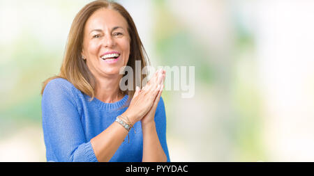 Schöne Frau mittleren Alters tragen winter Pullover über isolierte Hintergrund Klatschen und froh und glücklich applaudieren, lächelt stolz die Hände zusammen Stockfoto