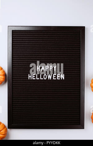 Happy Halloween Worte auf Schwarz schreiben strukturierte Board. Es ist im Rahmen mit kleinen gelben Kürbisse. Flach Stil. Stockfoto