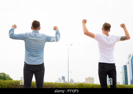 Zwei junge Mann mit erhobenen Armen im Freien Stockfoto