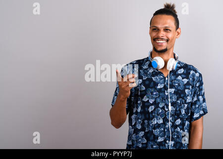 Junge Bartgeier schöner afrikanischer Mann Kopfhörer tragen gegen gr Stockfoto