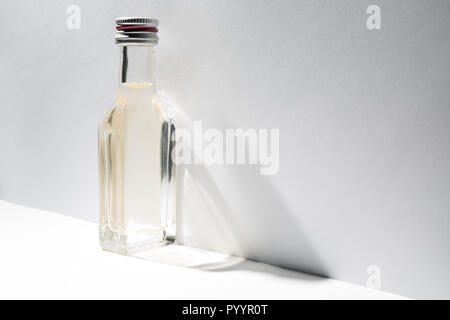 Eine Flasche Jahrgang Alkohol in der Nähe der Wand mit schrägen Schatten. Stockfoto
