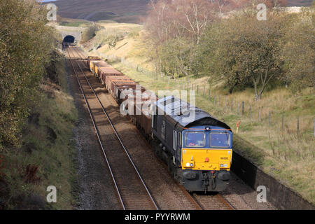 Class 66 diesel-elektrische Lok in DRS livery verlassen Blea Moor Tunnel der Eisenbahnlinie nach Carlisle mit einem Güterzug am 30. Oktober 2018 vereinbaren. Stockfoto