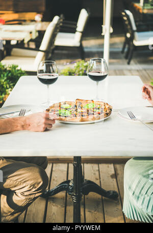 Leute genießen frische Pizza und Rotwein im Café im Freien Stockfoto