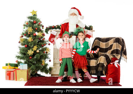 Kinder und Santa in der Nähe von Kamin und Weihnachtsbaum und Kamera isoliert auf weißem Stockfoto