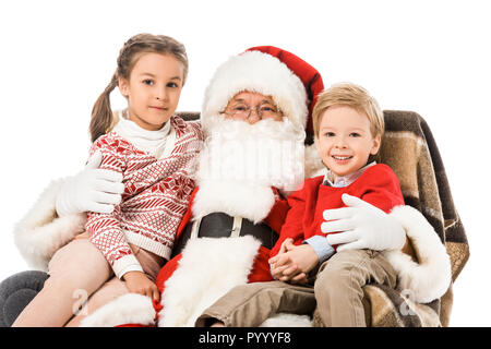 Kinder und santaembracing und die Kamera während der Sitzung in Sessel zusammen isoliert auf weißem Stockfoto