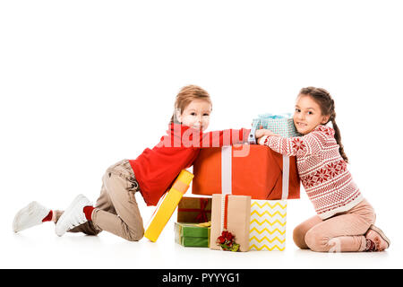 Gerne kleine Kinder sitzen auf dem Boden mit Haufen von Weihnachtsgeschenke isoliert auf weißem Stockfoto