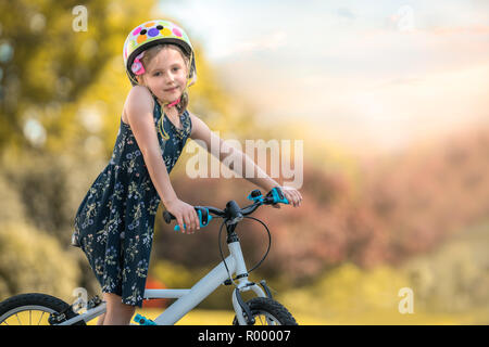 Portrait einer entzückenden jungen kaukasischen Mädchen mit ihrem Fahrrad in einem öffentlichen Park Stockfoto