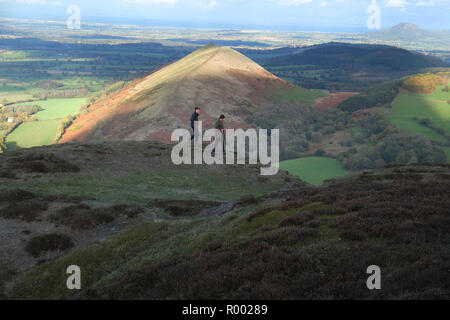 Zwei männliche Wanderer in der Nähe der Gipfel von Caer Caradoc, Church Stretton, Shropshire. Die Sonne leuchtet auf dem Höhepunkt der Lawley Hügel hinter Ihnen. In der weit entfernten Rechts ist die Wrekin Stockfoto