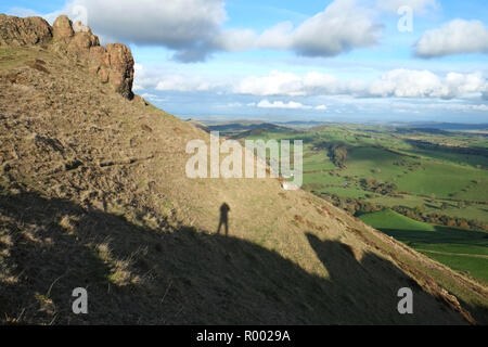 Schatten des Fotografen in der Nähe der Gipfel von Caer Caradoc, Church Stretton, Shropshire, Großbritannien. Auf der Suche nach Norden in Richtung offene Landschaft Stockfoto