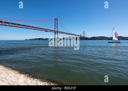 Segelboot auf den Fluss Tejo (Rio Tejo) mit Ponte 25 de Abril Suspension Bridge und die Statue von Christus, Cristo Rei, Lissabon, Portugal. Stockfoto