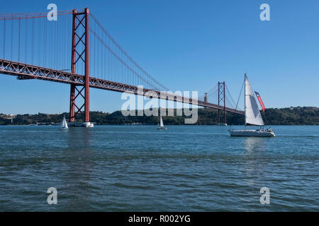 Segelboote auf den Fluss Tejo (Rio Tejo) mit Ponte 25 de Abril Suspension Bridge und die Statue von Christus, Cristo Rei, Lissabon, Portugal. Stockfoto