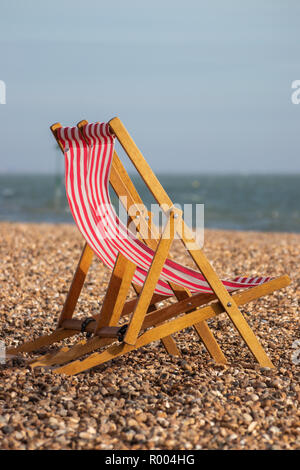 Rote und weiße Strand Liegestühle auf einer britischen Pebble Beach Stockfoto
