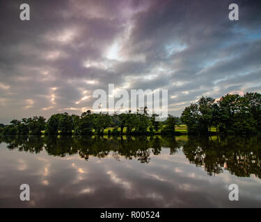 Zig Zag Wolkenbildung bei Sonnenuntergang über dem See auf dem ruhigen Gewässern widerspiegelt Stockfoto