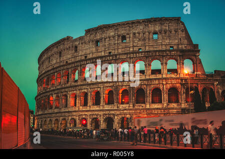 Rom, Italien. Leute, die sich vor Das beleuchtete Kolosseum bei Sonnenuntergang, berühmte Sehenswürdigkeiten in Rom bei Nacht Stockfoto