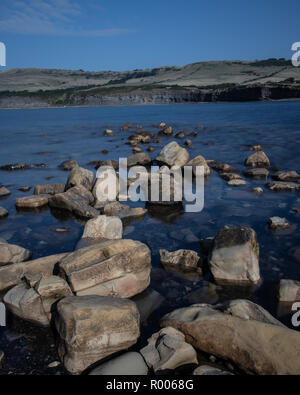 Ruhiges Wasser um Felsen im Meer mit Felsen im Hintergrund Stockfoto