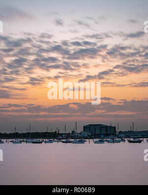 Sonnenuntergang über eine Marina mit Segelbooten auf ruhigen Gewässern im Vordergrund, Port Solent, Hampshire, Großbritannien Stockfoto