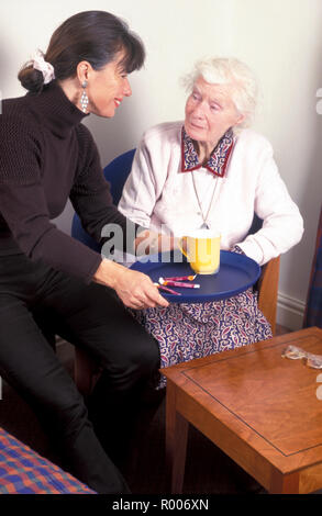 Pflegeperson weiblichen Erwachsenen, alten Dame Tee auf einem Tablett Stockfoto