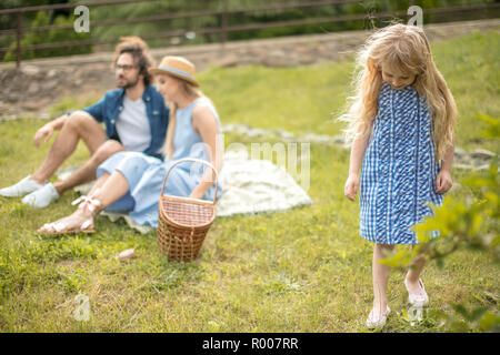 Glückliche Familie Picknick im Freien mit ihren niedlichen Tochter, blaue Kleidung, Frau mit Hut Stockfoto