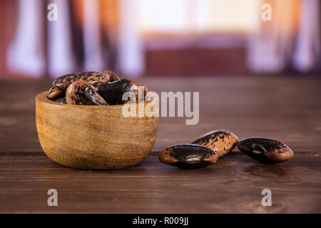 Menge ganze gesprenkelte Farbige butter Bohnen Painted Lady Scarlet runner Sorte mit Holzschale mit seidenen Vorhängen hinter Stockfoto