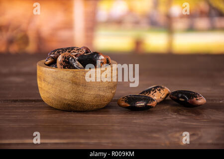 Menge ganze gesprenkelte Farbige butter Bohnen Painted Lady Scarlet runner Sorte mit Holzschale mit Karre im Hintergrund Stockfoto