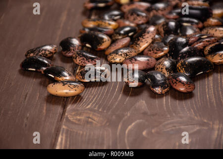 Menge ganze rohe gesprenkelte Farbige butter Bohnen Painted Lady Scarlet runner Vielfalt auf braunem Holz Stockfoto