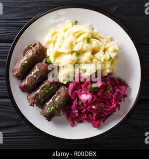 Rindfleisch Brötchen mit Senf, Speck, Gurken auf einem Teller serviert mit Kartoffelpüree und Rotkohl close-up. nach oben Ansicht von oben Stockfoto