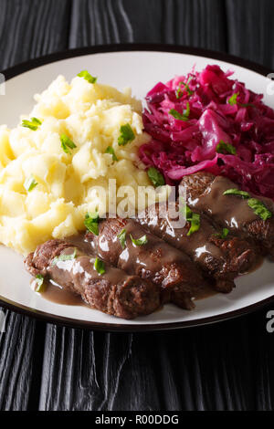 Rouladen oder rinderrouladen ist ein deutsches Rindfleisch, mit Speck, Zwiebeln, Senf und Gurken mit Kartoffelpüree und Rotkohl in der Nähe serviert auf einem Teller. Stockfoto