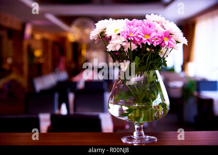 Ein Bouquet aus weißen und rosa Gänseblümchen in einem Glas Wasser. Stockfoto