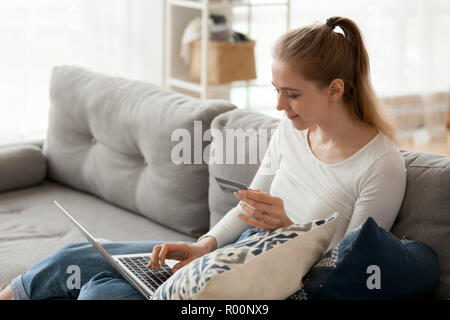 Junge Frau sitzt auf der mit Laptop und Kreditkarte couch Stockfoto