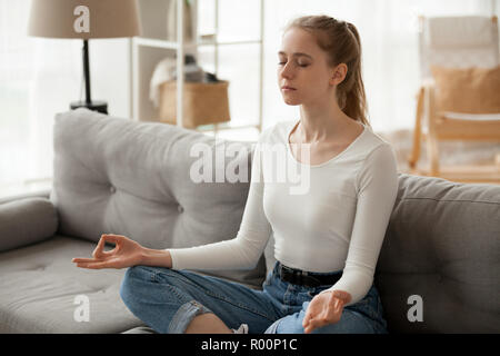 Frau Meditation sitzen auf der Couch zu Hause Stockfoto