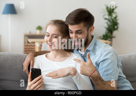 Paar in Liebe oder Freunde sitzen auf der Couch mit Smartphone Stockfoto