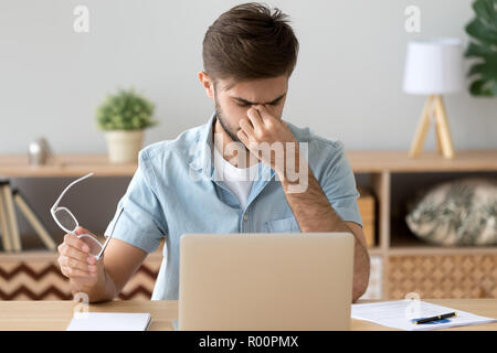 Müde Arbeiter hat eine Überanstrengung der Augen am Schreibtisch sitzen Stockfoto