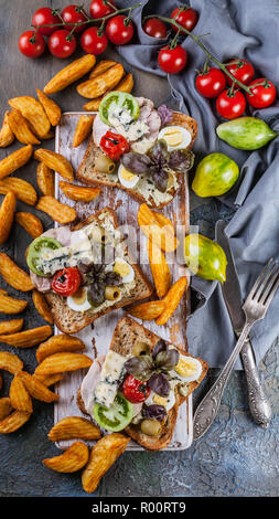 Leckere Toasts mit Avocado, Wachteleier, Tomaten, Dor Blauschimmelkäse und Pommes Frites. Das Thema Küche. Original serviert Gerichte Stockfoto