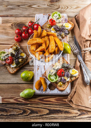 Leckere Toasts mit Avocado, Wachteleier, Tomaten, Dor Blauschimmelkäse und Pommes Frites. Das Thema Küche. Original serviert Gerichte Stockfoto