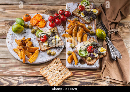 Leckere Toasts mit Avocado, Wachteleier, Tomaten, Dor Blauschimmelkäse und Pommes Frites. Das Thema Küche. Original serviert Gerichte Stockfoto