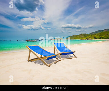 Schönen weißen Sandstrand. Stühle im Vordergrund, Fischerboote auf Hintergrund. Landschaft von Vietnam Stockfoto