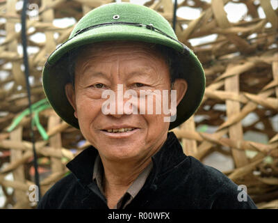 Im mittleren Alter vietnamesischen H'Mong Community Leader trägt ein North Vietnam Armee markröhre Helm an einem regnerischen Tag. Stockfoto