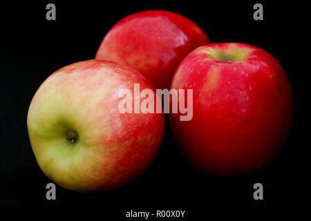 Drei pink lady Äpfel arrangiert auf Schwarz. Stockfoto