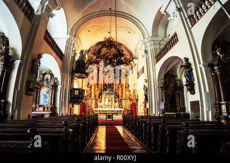 GRAZ, ÖSTERREICH, 15. Februar 2016: Innenraum der Kirche der Heiligen Dreifaltigkeit. Leere Sitze mit wunderschönen Altar. Kleine Kirche im Zentrum der Stadt Stockfoto