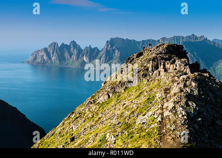 Wanderer auf dem Berg Husfjell, Blick auf die Bergkette Okshornan im Rücken, aus dem Meer aufragenden Gipfeln, Insel Senja, Troms, Nordnorwegen, Stockfoto