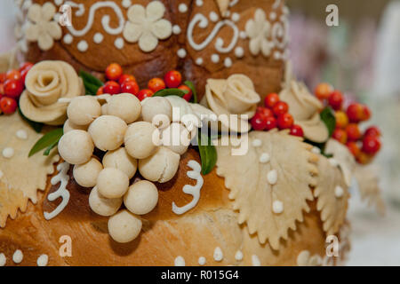 Brot, mit Blumen und Trauben aus dem Teig dekoriert. Gebäck für feierliche Anlässe. Stockfoto