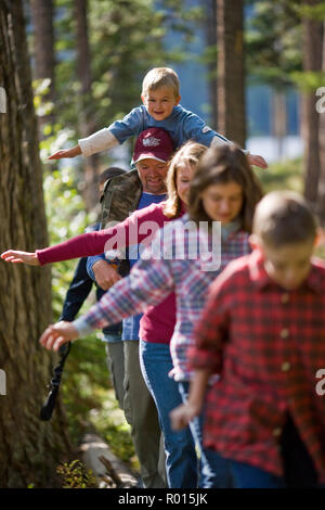 Glückliche Familie zu Fuß hinter einander durch einen Wald. Stockfoto